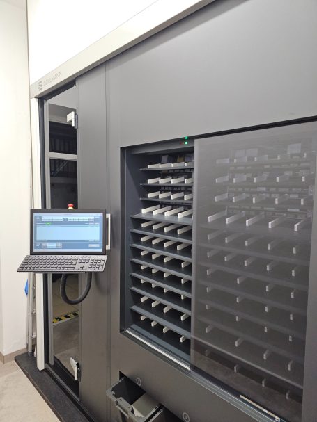 Bedieneinheit Automatisiertes Lagerregal mit Monitor und Fächern für Lagerwaren.