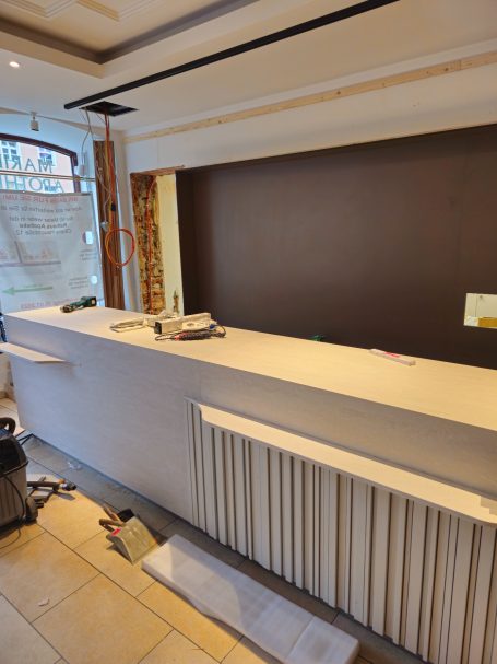 Moderne Empfangstheke in einem Innenraum, beige mit Holzakzenten.